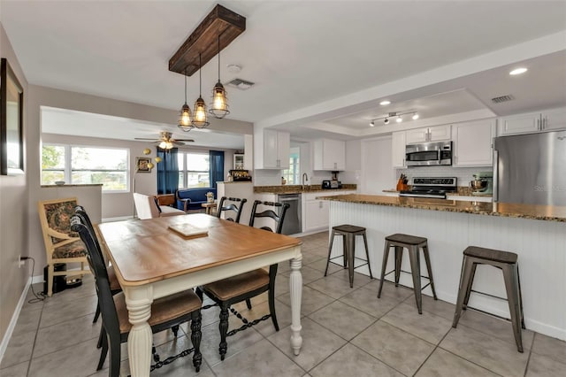 dining space featuring light tile patterned floors, a tray ceiling, sink, and ceiling fan