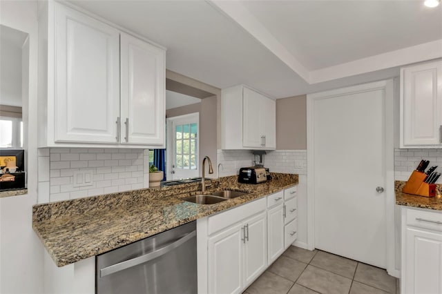 kitchen featuring white cabinetry, stainless steel dishwasher, sink, and dark stone countertops