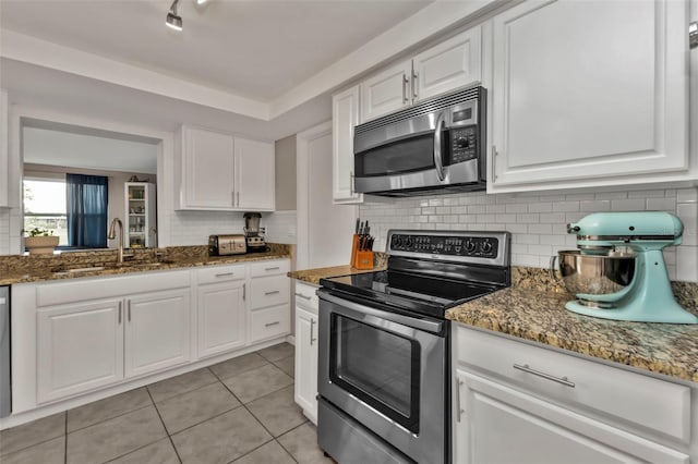 kitchen featuring white cabinetry, sink, dark stone counters, and appliances with stainless steel finishes