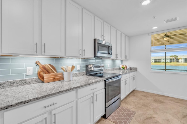 kitchen featuring light stone counters, backsplash, stainless steel appliances, and white cabinets