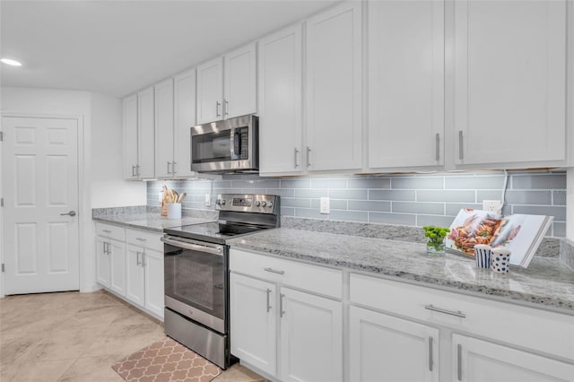 kitchen featuring stainless steel appliances, light stone countertops, decorative backsplash, and white cabinets