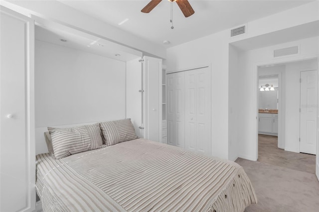 bedroom featuring light colored carpet, a closet, ceiling fan, and ensuite bathroom