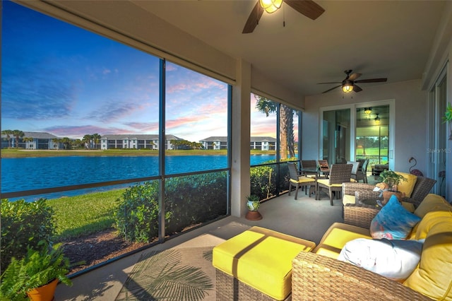 sunroom / solarium featuring ceiling fan and a water view