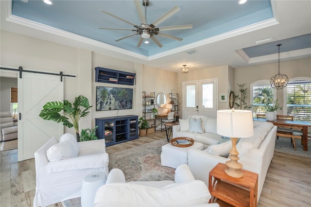 living room featuring light hardwood / wood-style flooring, a raised ceiling, and a barn door