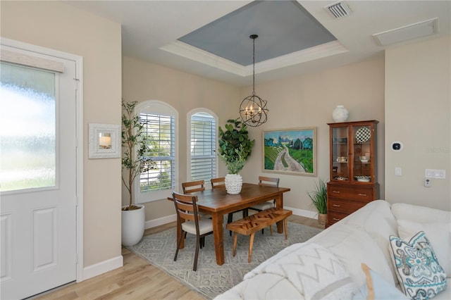 dining room with an inviting chandelier, a tray ceiling, and light hardwood / wood-style floors