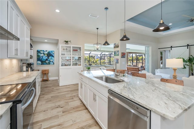 kitchen featuring white cabinetry, stainless steel appliances, a barn door, and sink