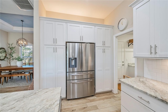 kitchen with pendant lighting, white cabinets, stainless steel refrigerator with ice dispenser, light stone countertops, and light hardwood / wood-style flooring