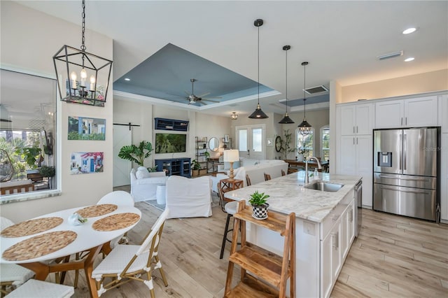 kitchen with sink, stainless steel appliances, white cabinets, and a center island with sink