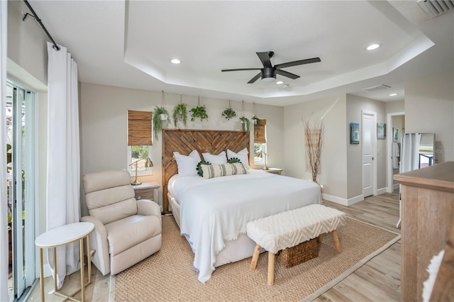 bedroom featuring a raised ceiling, ceiling fan, and light hardwood / wood-style floors