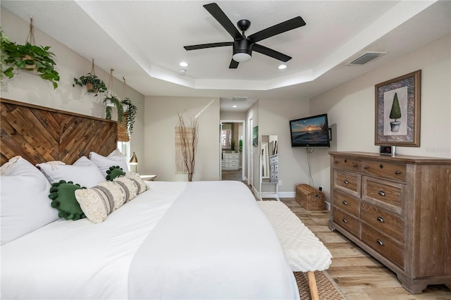 bedroom featuring light hardwood / wood-style floors, a raised ceiling, and ceiling fan