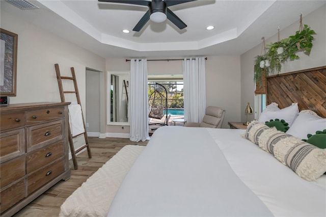 bedroom with a raised ceiling, access to outside, ceiling fan, and light hardwood / wood-style flooring