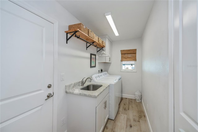 laundry area with cabinets, sink, washer and dryer, and light wood-type flooring