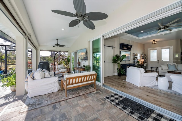 sunroom with plenty of natural light, a barn door, and a tray ceiling