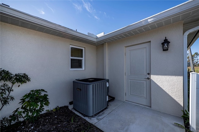 view of exterior entry featuring central AC and a patio area