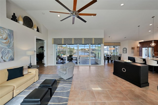 living room with a high ceiling, a water view, a healthy amount of sunlight, and ceiling fan