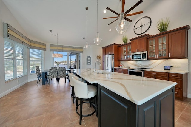 kitchen with pendant lighting, sink, backsplash, stainless steel appliances, and a large island with sink