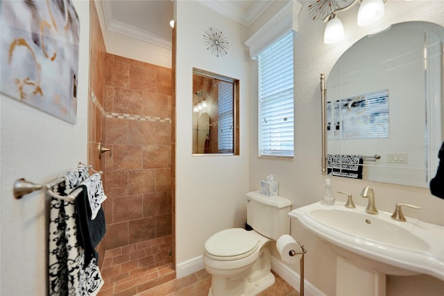 bathroom with ornamental molding, toilet, a tile shower, and plenty of natural light