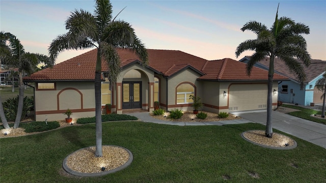 view of front of property featuring french doors, a garage, and a lawn