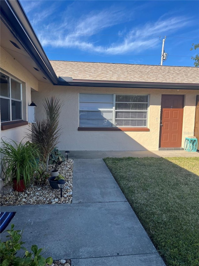 view of exterior entry featuring a lawn