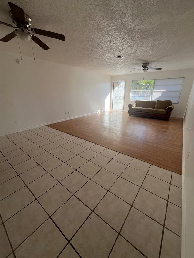 empty room featuring ceiling fan, light hardwood / wood-style floors, and a textured ceiling