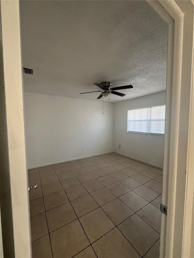 spare room with light tile patterned floors, a textured ceiling, and ceiling fan