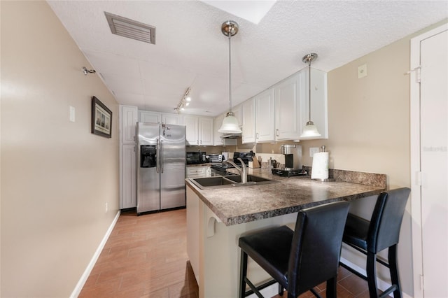 kitchen featuring stainless steel fridge with ice dispenser, decorative light fixtures, white cabinetry, a kitchen breakfast bar, and kitchen peninsula