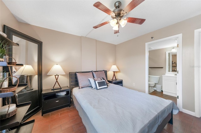 bedroom with dark wood-type flooring, ceiling fan, and ensuite bath