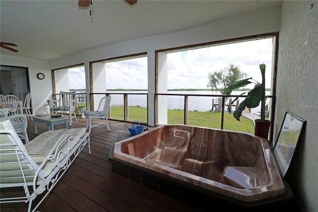 sunroom featuring a hot tub, a water view, and ceiling fan