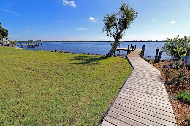 dock area with a lawn and a water view