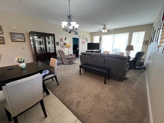 carpeted living room featuring ceiling fan with notable chandelier