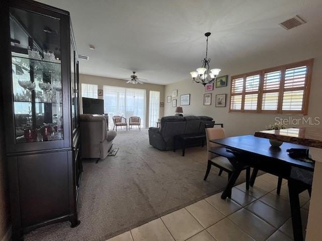 dining space with carpet and ceiling fan with notable chandelier