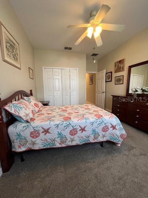 carpeted bedroom with ceiling fan and a closet