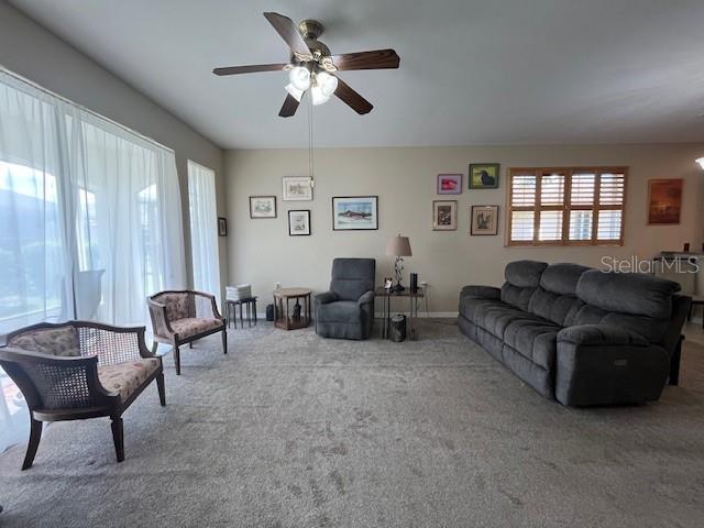 carpeted living room with ceiling fan