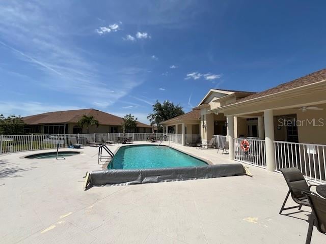 community pool featuring a hot tub, fence, and a patio area