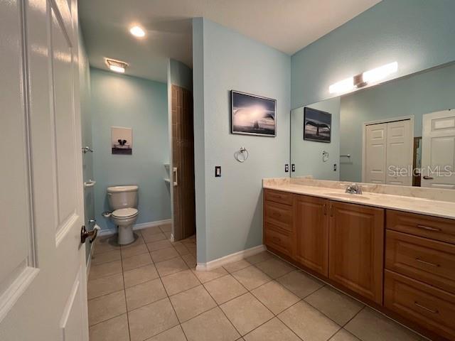 full bath with tile patterned flooring, toilet, baseboards, and vanity