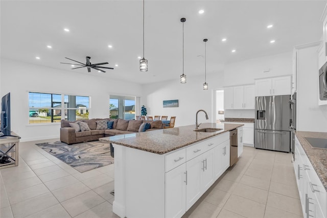 kitchen featuring sink, an island with sink, stainless steel appliances, light stone countertops, and white cabinets