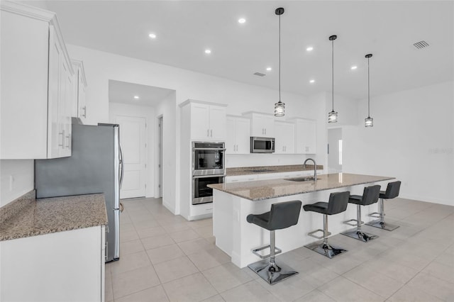 kitchen featuring pendant lighting, white cabinetry, sink, light stone counters, and stainless steel appliances