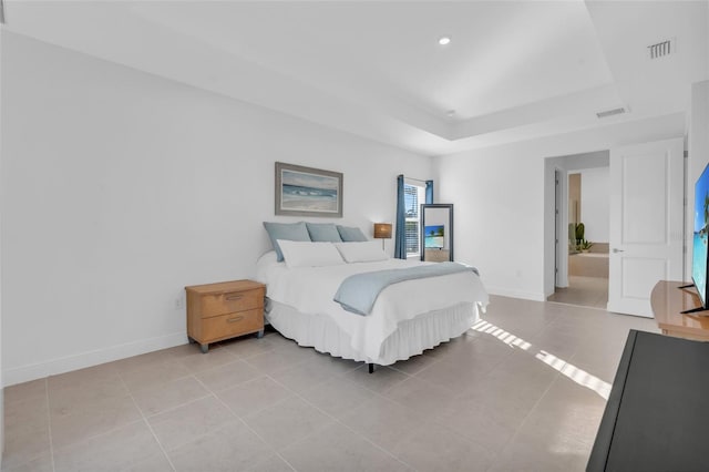 bedroom featuring a tray ceiling, connected bathroom, and light tile patterned floors