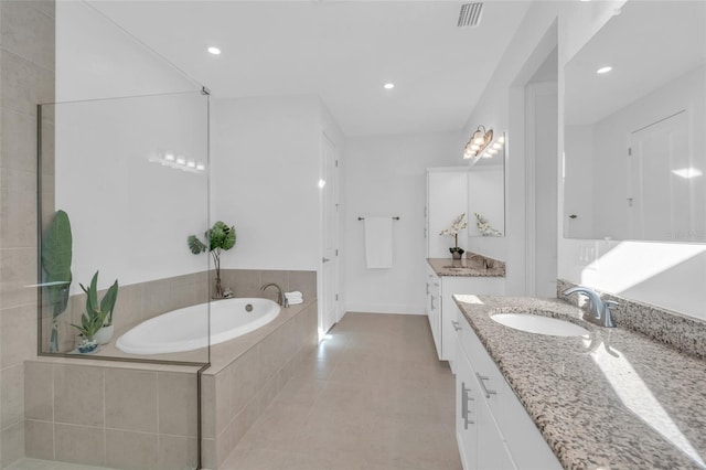 bathroom featuring vanity, tiled bath, and tile patterned flooring