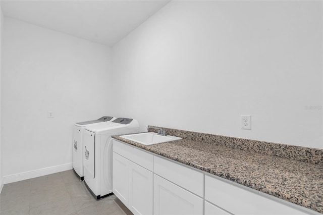 clothes washing area with cabinets, washing machine and clothes dryer, and sink