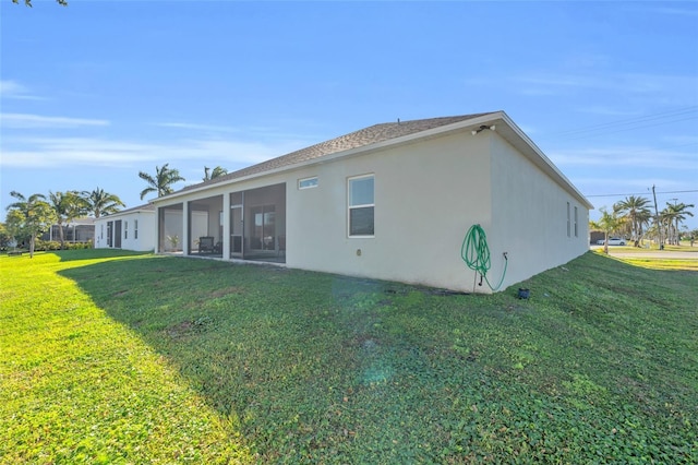 rear view of house featuring a sunroom and a lawn