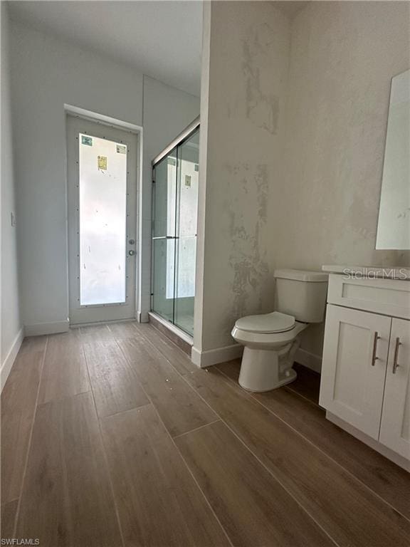 bathroom featuring vanity, hardwood / wood-style floors, toilet, and walk in shower