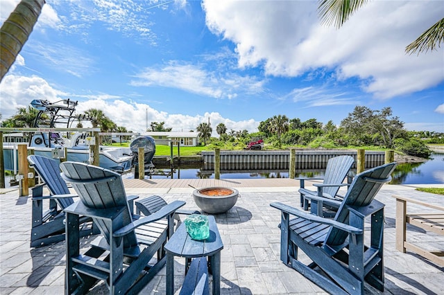 view of patio / terrace with a water view, an outdoor fire pit, and a dock