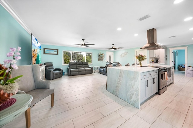 kitchen with electric range oven, island range hood, white cabinetry, ceiling fan, and crown molding