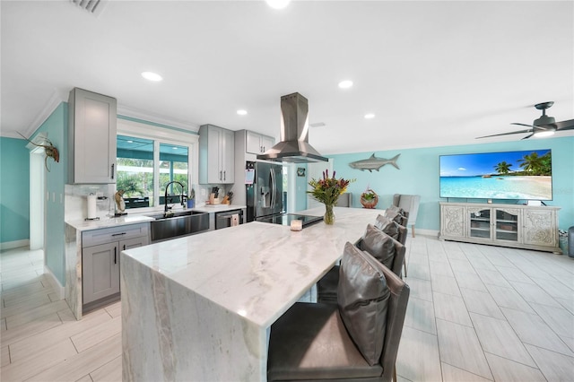 kitchen featuring sink, a kitchen island, gray cabinets, and island exhaust hood