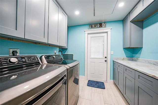 clothes washing area with cabinets and washer and dryer