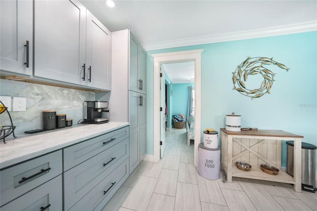 kitchen featuring crown molding, light stone counters, and decorative backsplash