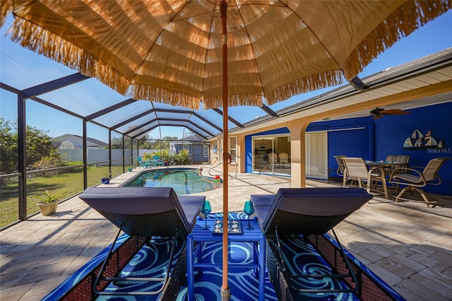 view of patio featuring ceiling fan and glass enclosure