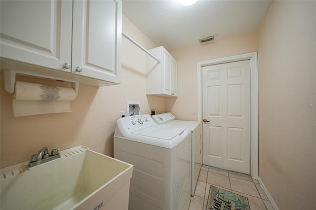 laundry room with light tile patterned flooring, washer and dryer, sink, cabinets, and a textured ceiling