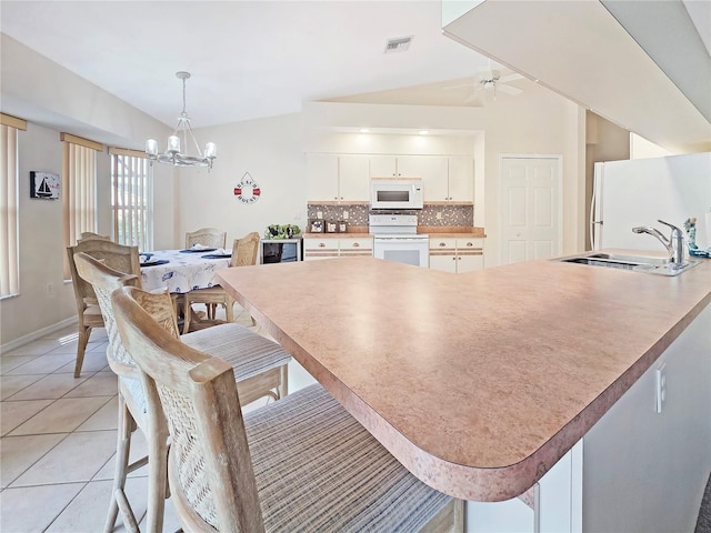 18395 Edgewater Dr, Port Charlotte, FL 33948 - kitchen with visible vents, white appliances, a kitchen bar, tasteful backsplash, and a sink